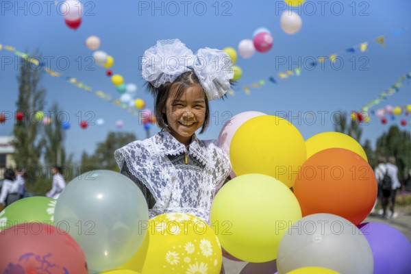 Happy schoolgirl with colourful balloons on the first day of school, Issyk-Kul region, Kyrgyzstan, Asia