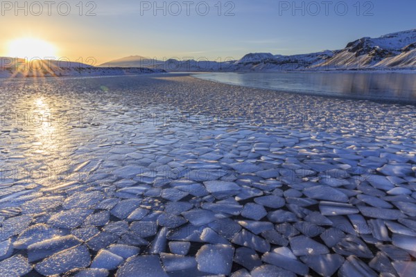 Ice floes on a lake in front of snowy mountains, sunset, backlight, evening light, snow, winter, Snaefellsnes, Vesturland, Iceland, Europe