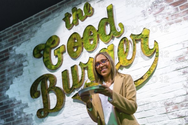 Low angle view portrait of a latin woman holding a delicious burger in a restaurant