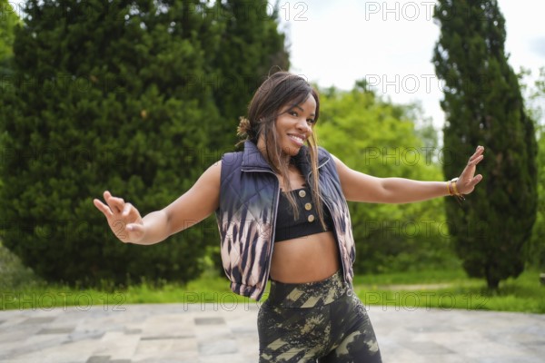 Cool female latin dancer gesturing with open arms dancing salsa alone in a park