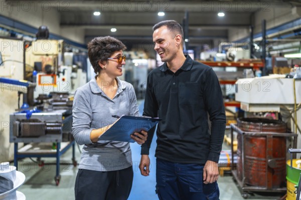 Female boss and worker talking happily and animatedly in a cnc factory