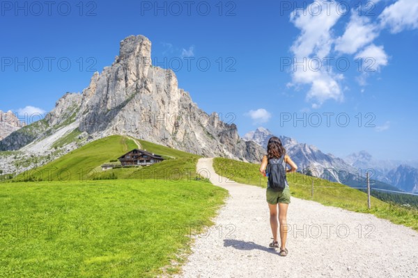 Female tourist walking on a path enjoying the scenic landscape of the giau pass in the dolomites, italy, during a sunny summer day