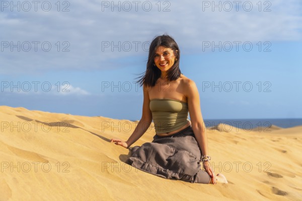 Young woman relaxing and enjoying a sunny day sitting on the sand of the maspalomas dunes in gran canaria, spain