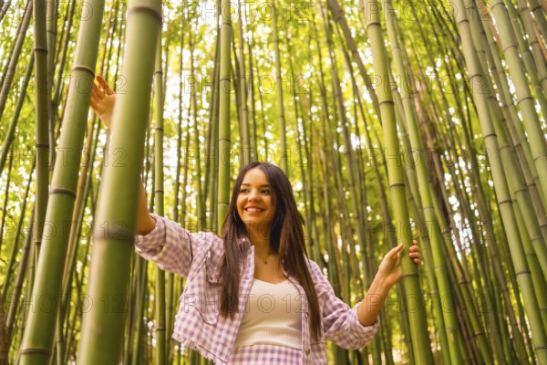 Young caucasian girl with a pink skirt in a bamboo forest. Enjoying summer holidays in a tropical climate, walking in the forest grabbing the trunks of bamboo and smiling