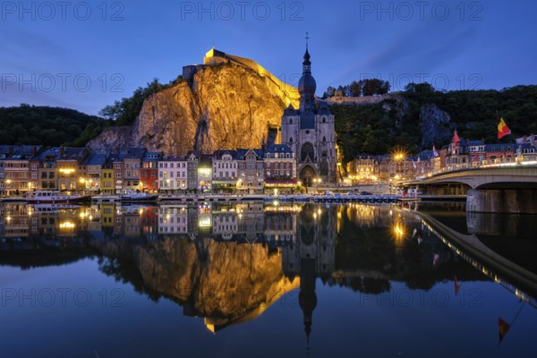 Night view of Dinant town, Collegiate Church of Notre Dame de Dinant over River Meuse and Pont Charles de Gaulle bridge and Dinant Citadel illuminated in the evening. Dinant, Belgium, Europe