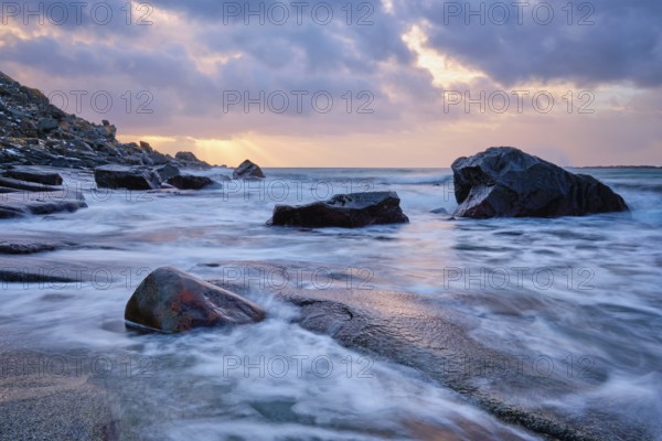 Rocks on beach of fjord of Norwegian sea in winteron sunset. Utakliev beach, Lofoten islands, Norway, Europe