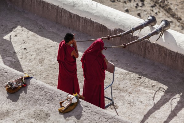 THIKSEY, INDIA, SEPTEMBER 4, 2011: Two Tibetan Buddhist monks blowing Tibetan horn (dungche) during morning pooja, Thiksey gompa, Ladakh, India, Asia