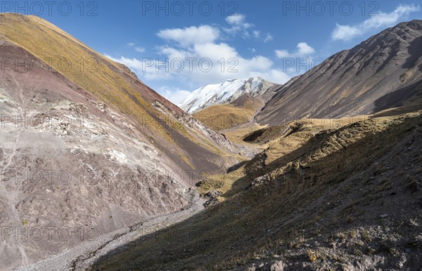Valley with mountain stream between high mountains in autumn, mountain landscape with glaciated peak Pik ITMO University, Trans Alay Mountains, Pamir Mountains, Osh Province, Kyrgyzstan, Asia