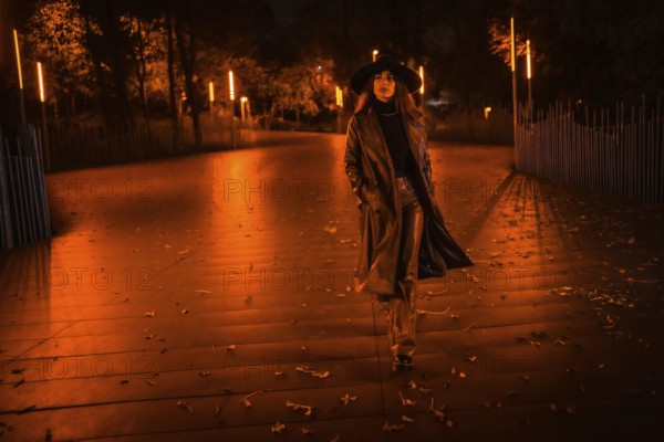 Girl in a hat walking calmly through a park on a winter night. Enjoying the solitude of the night in a fashionable pose