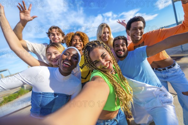 Multi-ethnic friends smiling at camera while taking a funny selfie in the city