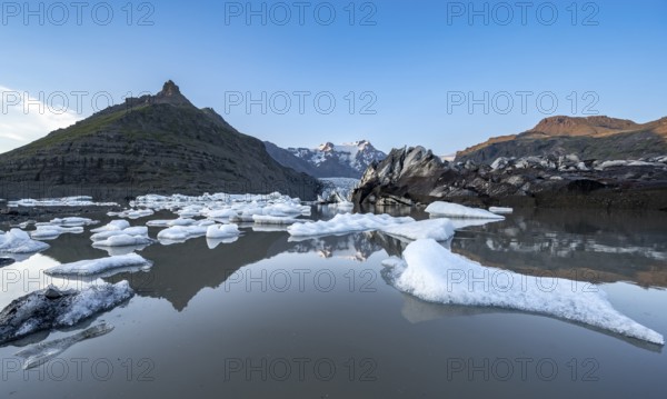 Reflection in the Svínafellslon glacier lagoon with ice floes, Svínasfellsjökull glacier tongue, glaciated mountain peak Hrútfjallstindar in the background, at sunset, Svínafell, Iceland, Europe