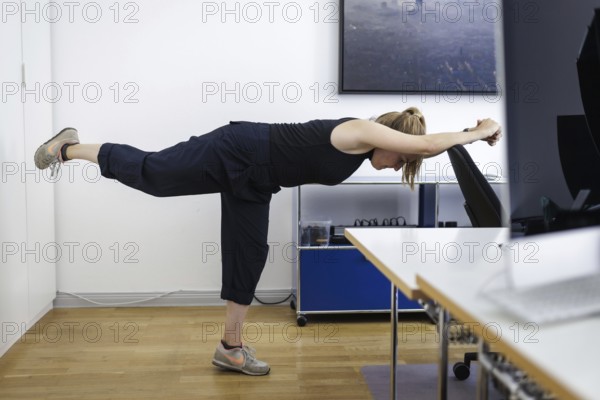 A woman does sports exercises at her workplace in an office in Berlin, 08/08/2024