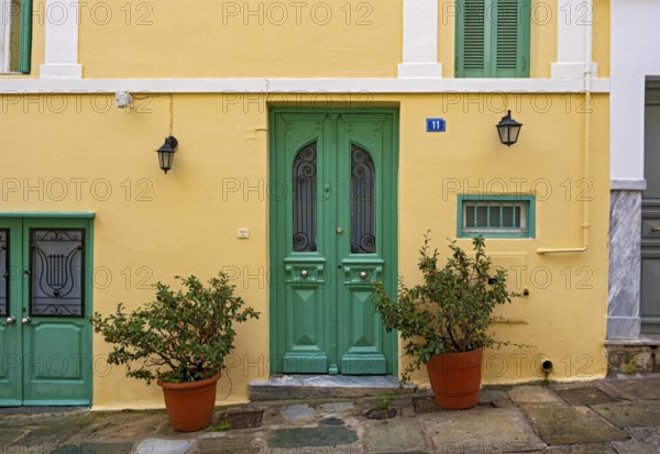 A charming house with a yellow facade and green doors in the Plaka district of Athens, Greece, Europe