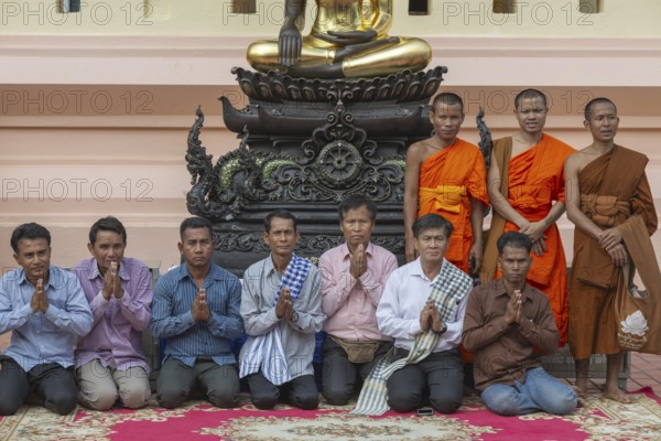 Monks and Laotians in front of a Buddha statue, Bhumispara-mudra, Buddha Gautama at the moment of enlightenment, Wat Ong Teu, Vientiane, Laos, Asia