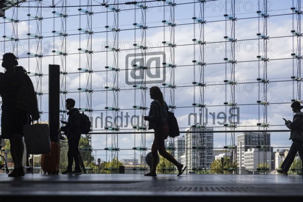 Central station, travellers in front of the glass facade with the logo of Deutsche Bahn AG. Berlin, Germany, Europe
