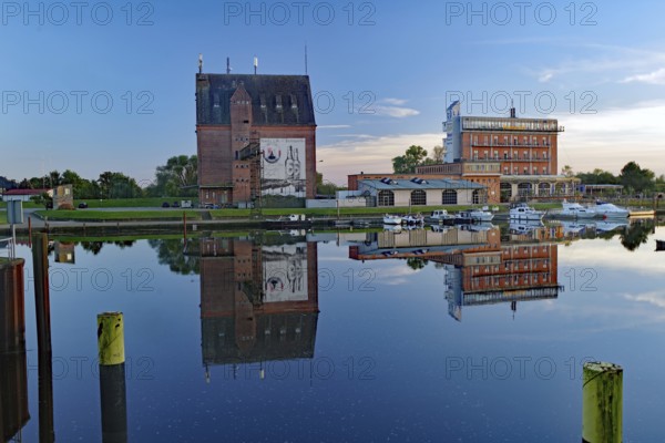 Historic buildings on the waterfront with boats and reflected evening sky in calm harbour water, Tourism, Hotel Dömitz, Elbe, Brandenburg, Germany, Europe