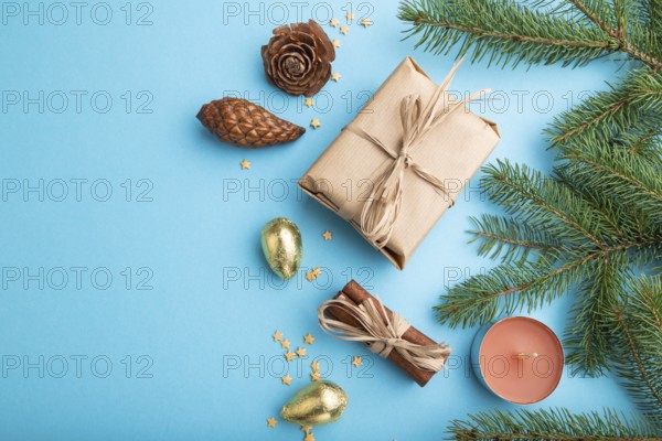 Christmas or New Year composition. Decorations, box, cinnamon, cones, fir and spruce branches, on a blue paper background. Top view, close up, flat lay