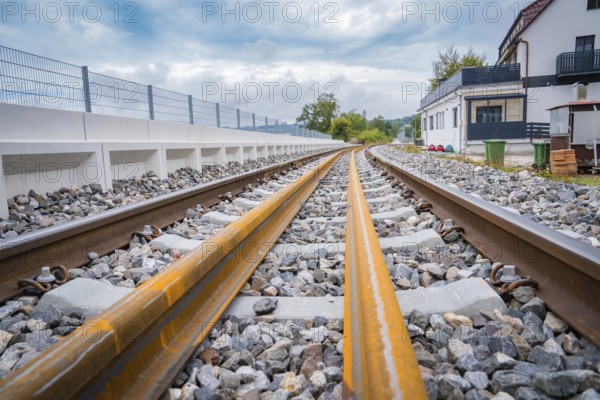A railway track runs through a landscape with buildings in the background, under a cloudy sky, track construction, rail delivery for Hermann Hessebahn, Calw, Black Forest, Germany, Europe