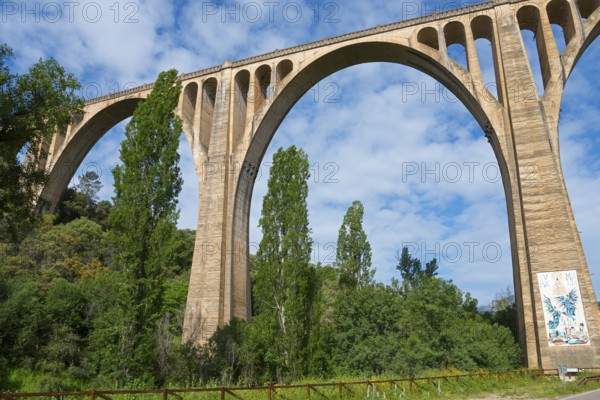 Steinbrücke mit großen Bögen über einem Wald, blauer Himmel und weiße Wolken, Aquädukt, Guadalupe, Provinz Cáceres, Caceres, Extremadura, Spanien