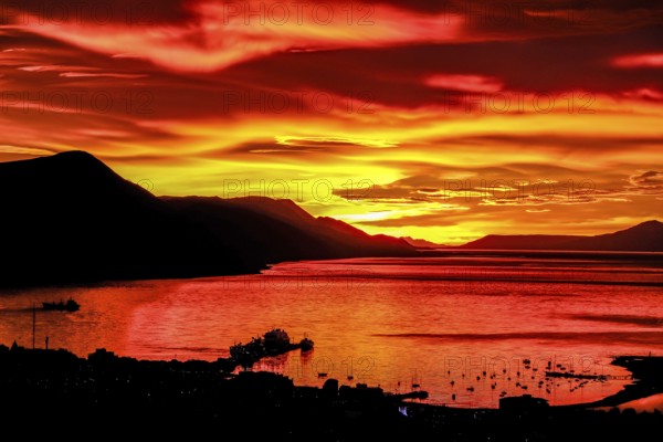 Ushuaia, Tierra del Fuego, Argentina, Glowing red sunrise over the Beagle Channel, the Beagle Channel is a natural waterway at the southern tip of South America that connects the Atlantic Ocean with the Pacific Ocean. Ushuaia is the southernmost city in the world, the end of the world. Behind mountain range on the island of Navarino in Chile, Dientes de Navarino, South America