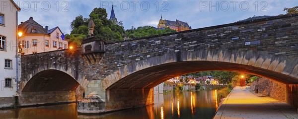 Town view of Vianden with the old stone bridge over the river Our and the castle in the evening, Grand Duchy of Luxembourg