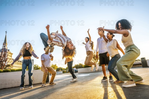 Man jumping dancing free style surrounded by multi-ethnic friends in the city during sunset
