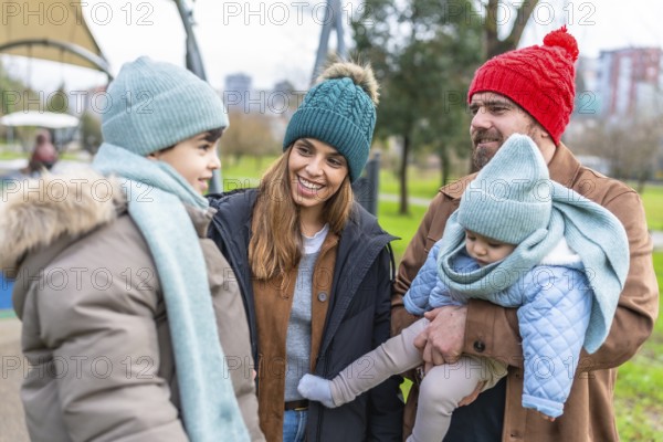 Smiling family wearing winter clothes spending time together at the playground on a cold day