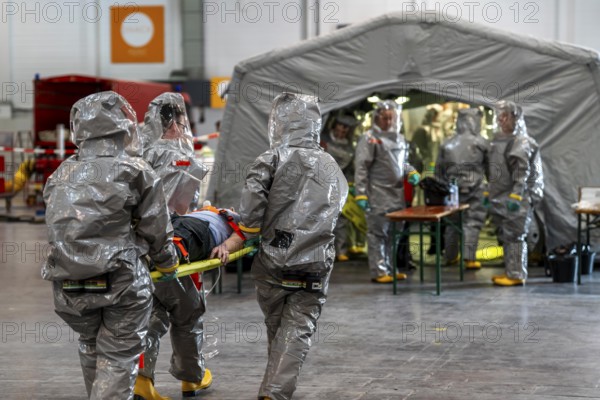 Decontamination of injured persons after an assumed accident involving hazardous substances, fire brigade and aid organisations practise setting up and operating a decontamination station, injured persons are sighted and then washed in a special shower tent to remove possible hazardous substances and chemicals in order to avoid further injuries, the emergency services wear special, ventilated protective suits, large-scale exercise by the Essen fire brigade