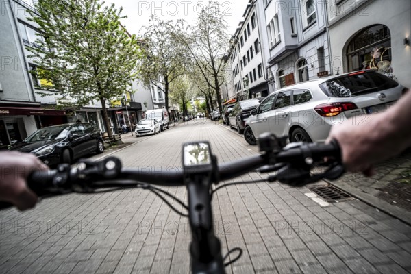 Cycling in the city, inner-city street, cycle lane, bicycles have priority, two-lane traffic with parked cars on both sides, cyclists' perspective, Essen, North Rhine-Westphalia, Germany, Europe