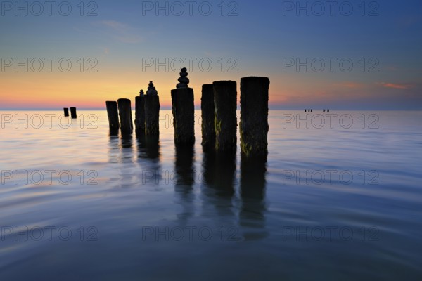 Stone pyramids on old groynes with algae in the water on the Baltic Sea beach at sunset, Wustrow, Fischland-Darß-Zingst peninsula, Mecklenburg-Vorpommern, Germany, Europe