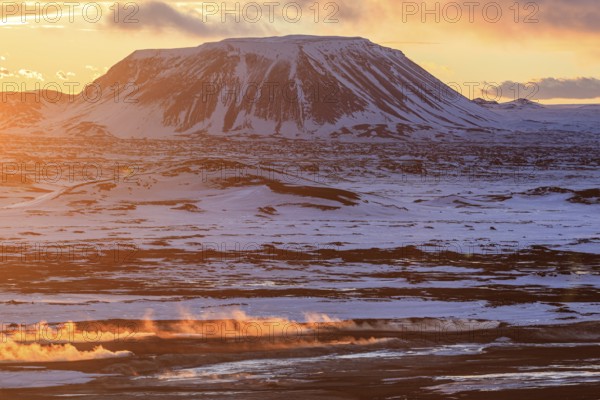 Hot springs and geothermal area in front of mountain landscape in winter, sunbeams, cloudy mood, Hverir, Namafjall, Myvatn, Iceland, Europe
