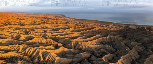 Landscape of eroded hills, badlands at sunset, Lake Issyk Kul in the background, aerial view, Canyon of the Forgotten Rivers, Issyk Kul, Kyrgyzstan, Asia