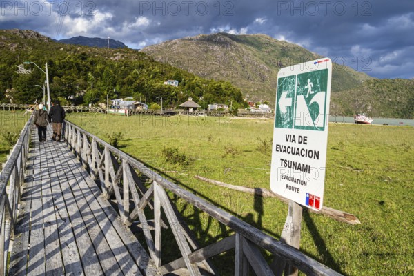 Signpost showing evacuation route in case of a tsunami, wooden boardwalk of Caleta Tortel, Aysen region, Patagonia, Chile, South America