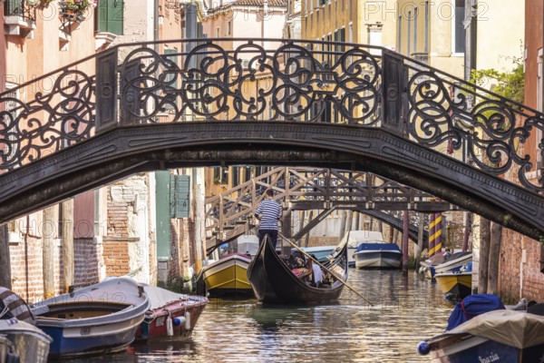 Venetian gondola with gondolier travelling on the canals of Venice, Venice, Italy, Europe