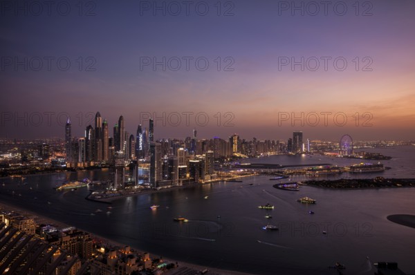 Night shot, view from The View At the Palm viewing platform of skyline with Princess Tower, Elite Residence, Ain Dubai Ferris wheel, luxury yacht OPERA owned by Sheikh Mansour bin Zayed Al Nahyan from the ruling family of the Emirate of Dubai, anchored in front of EMAAR Beachfront, logo, DAMAC, evening mood, Dubai Marina, Dubai, United Arab Emirates, VAR, Asia