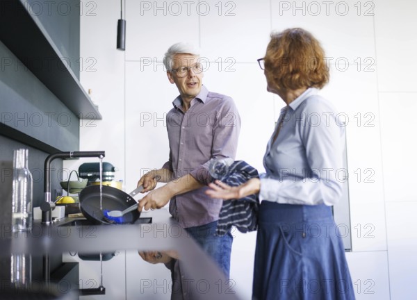 Symbolic photo. An elderly couple stand in the kitchen and do the washing up together. Berlin, 13.08.2024