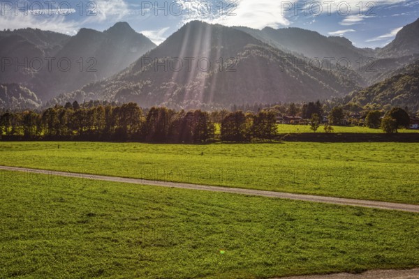 Landscape with green fields and forests in front of imposing mountains under a sunny sky, Klobenstein