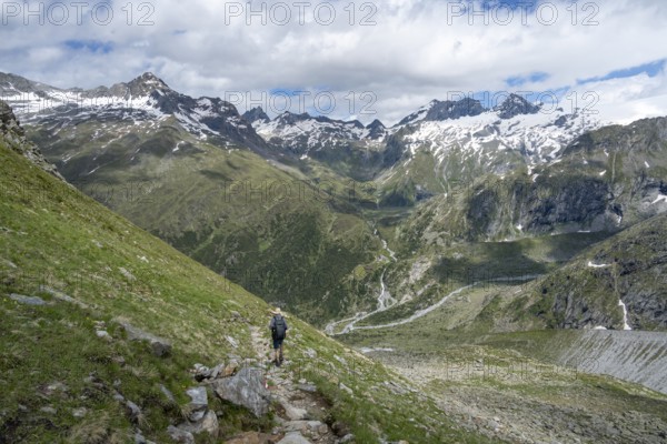 Mountaineer on a hiking trail in front of a picturesque mountain landscape, rocky mountain peaks with snow, valley Zemmgrund with Zemmbach, mountain panorama with summit Zsigmondyspitze and Großer Mörchner, Berliner Höhenweg, Zillertal Alps, Tyrol, Austria, Europe