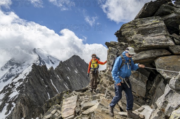 Two mountaineers on a hiking trail secured with a rope, glaciated summit Großer Möseler in the background, descent from the summit of Schönbichler Horn, Berliner Höhenweg, Zillertal Alps, Tyrol, Austria, Europe