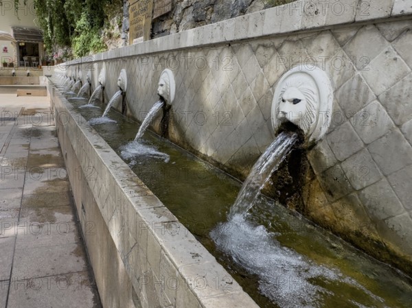 Partial view of lion fountain Venetian fountain Kefalovrisi with 25 gargoyles in the shape of lion's head lion's head below collecting basin for drinking water on main square of village Spili with drinking water, Spili, Crete, Greece, Europe