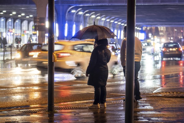 Illuminated subway at the main railway station, pedestrians at a pedestrian crossing, rainy weather, city centre, in the evening, Essen, North Rhine-Westphalia, Germany, Europe
