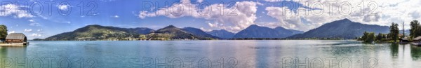 Clear water of a lake with surrounding mountains, on a sunny day with blue sky and white clouds, Tegernsee, Panorama