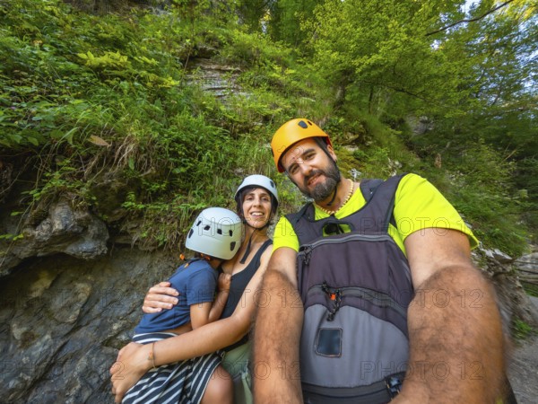 Happy family wearing helmets and backpacks taking a selfie while hiking in vintgar gorge near bled, slovenia
