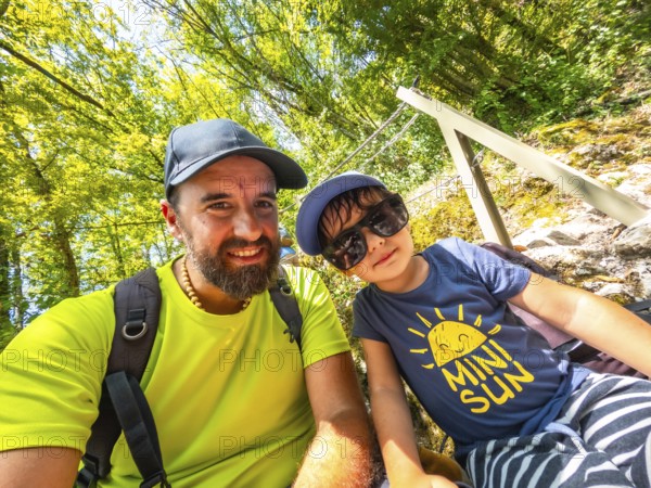 Father and son taking a selfie while hiking in a lush green forest, enjoying their summer vacation in the beautiful tolmin gorge, slovenia