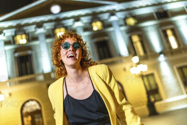 Cool woman smiling at camera while dancing in the city street at night