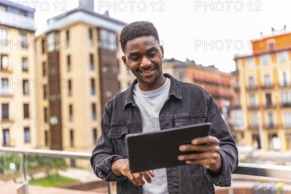 Happy african man touching the screen of a digital tablet and smiling outdoors in the city