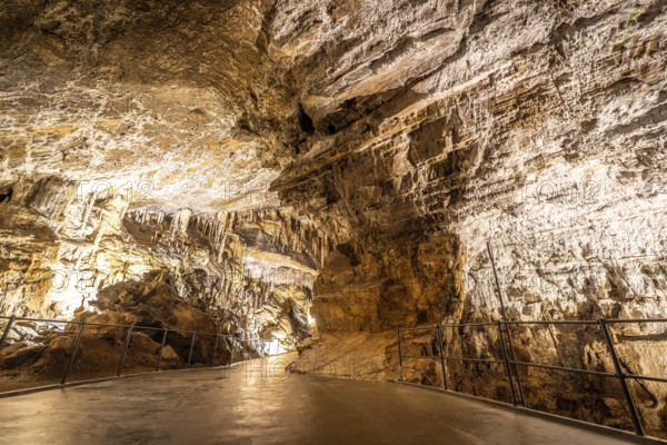Pathway winding through illuminated postojna cave, showcasing breathtaking stalactites and stalagmites formations