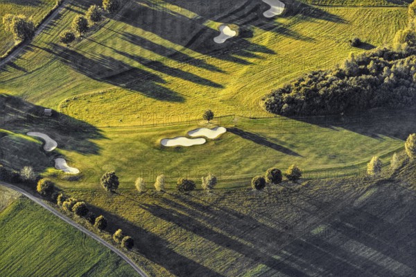 Aerial view from a hot air balloon of a golf course surrounded by trees and long shadows, Wenden, North Rhine-Westphalia, Germany, Europe