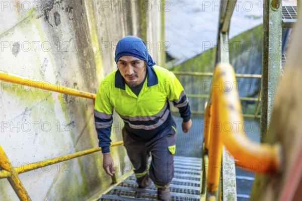 Top view of a latin man worker walking up stairs outside a recycling plant building