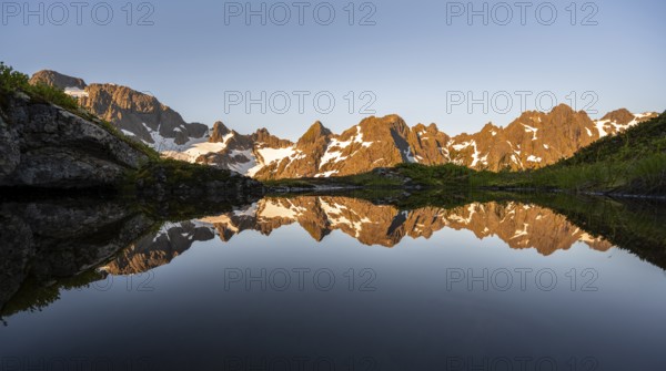 Rocky mountain peaks reflected in a small pond, mountain landscape with alpenglow at sunrise, at the Trollfjord Hytta, at the Trollfjord, Lofoten and Vesterålen, Nordland, Norway, Europe